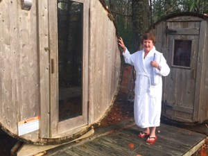 a woman in a white robe standing by a round outside sauna at the Trout Point Lodge