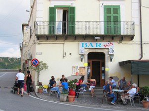 couple walking past people at a bar in Accettura