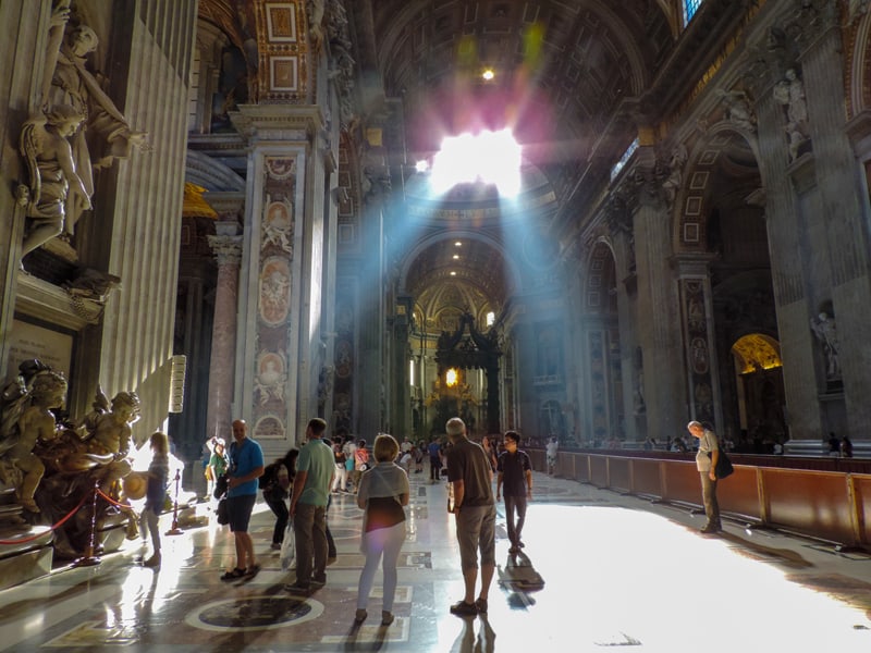 people in a basilica where light is shining down on them
