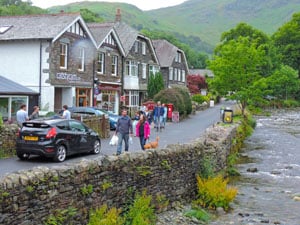 people walking along a brook in a village - one of the attractions of the Lake District