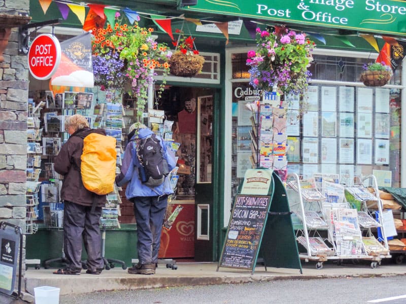 people at a shop front buying postcards