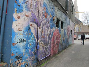 a man standing near a mural on a building