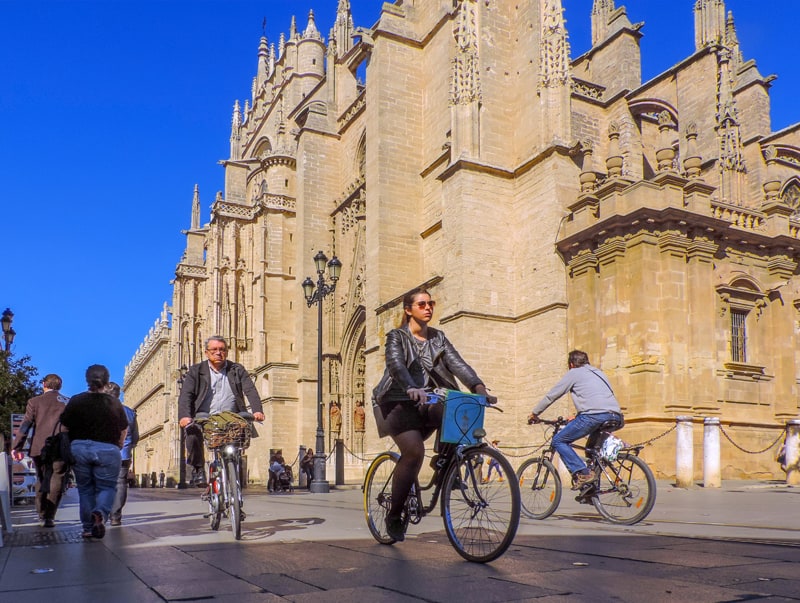 people on bikes near a cathedral, one of the things to do in Seville