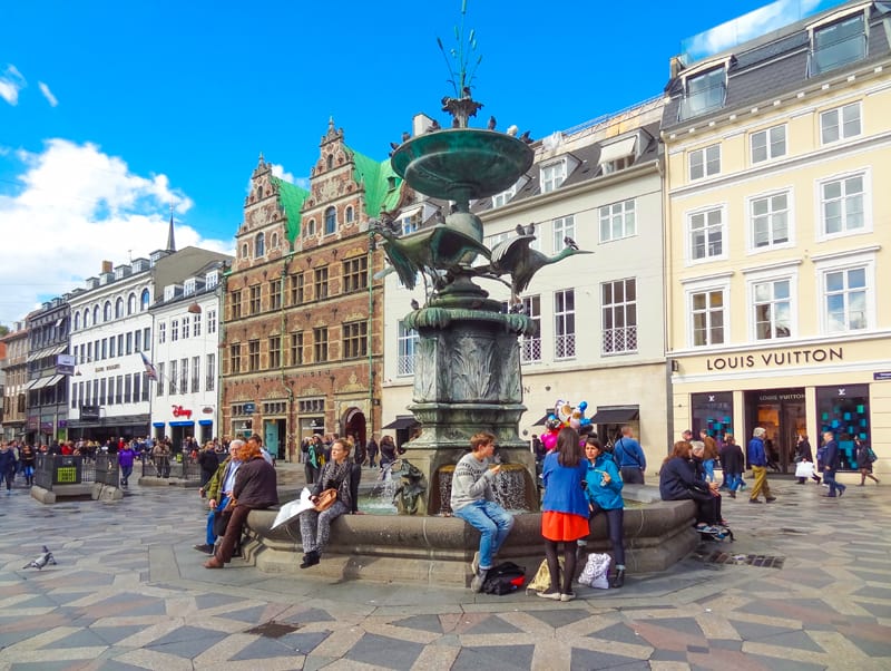 people sitting around an ornate fountain seen during one day in Copenhagen