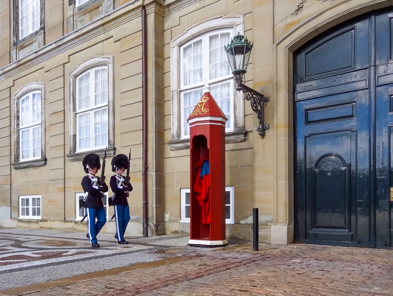 Palace guards walking past a red guard booth.