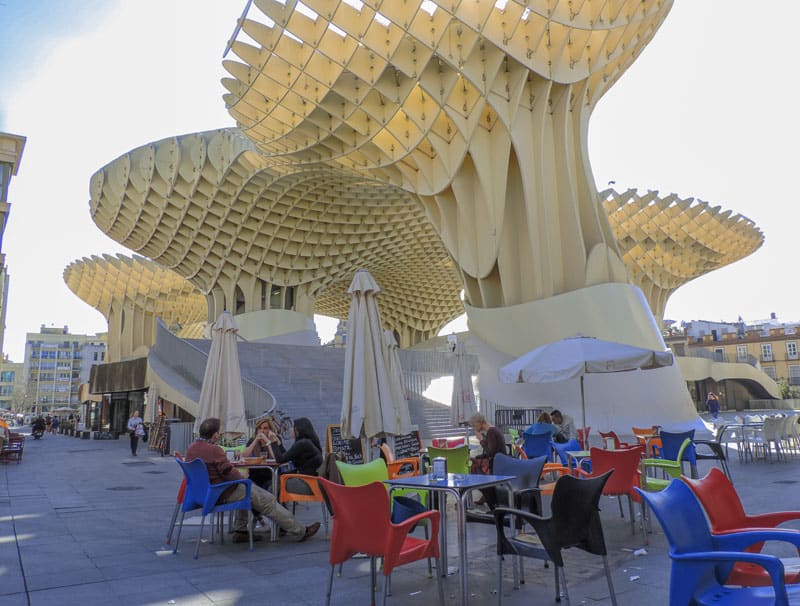 people sitting at tables beneath a large ornate parasol