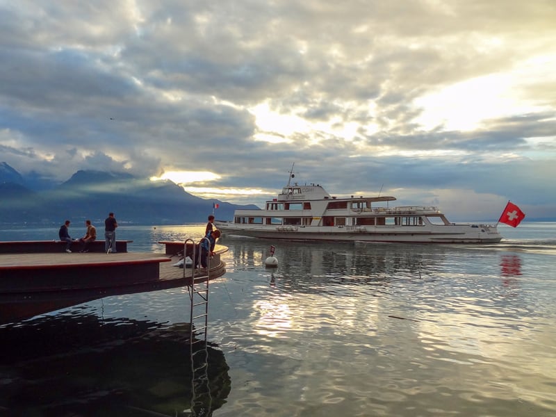 an old boat passing people on a pier in Montreux Switzerland