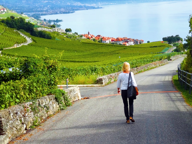 a woman walking down a rod through vineyards in Montreux Switzerland