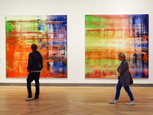 2 people walking by murals in an art museum