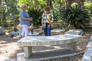 women looking at a grave site of a celebrity, one of the things to do in Savannah