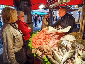 a fishmonger talking to two women in one of the best places to visit in Venice