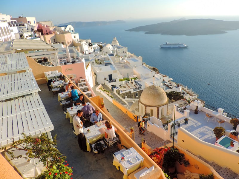 people in a restaurant overlooking a ship in a bay during 24 Hours On Santorini