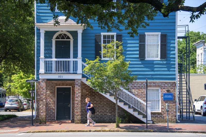 a woman walking by a house painted bright blue