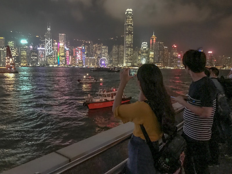 a couple looking at the skyline of a colorful city - A symphony of lights in Hong Kong