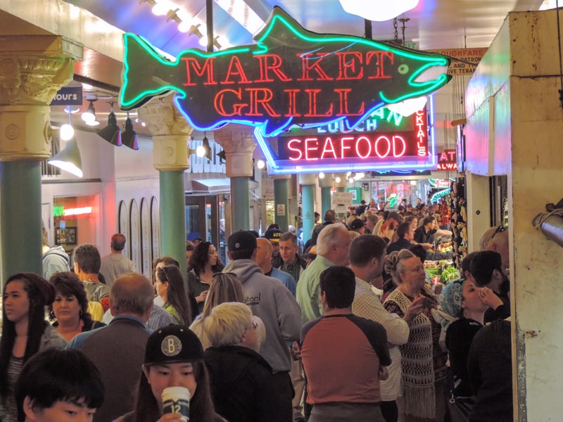 a crowd of people visiting a seafood market - one of the things to do in Seattle