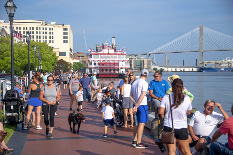 people sitting along a river front, one of the things to do in Savannah