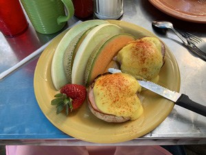 Eggs Benedict with slices of melon