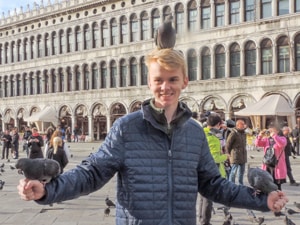 a boy with a pigeon on his head in one of the best places to visit in Venice