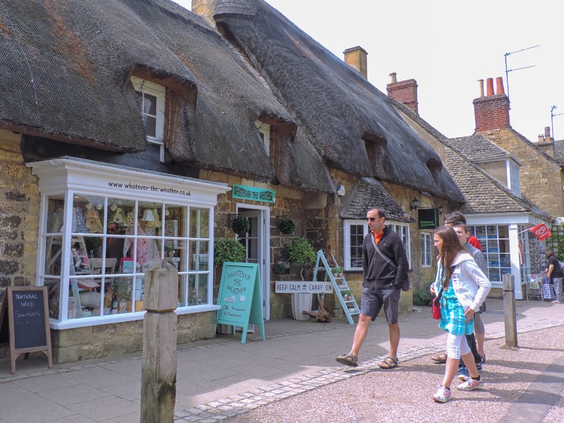 a family walking by shops with thatched roofs