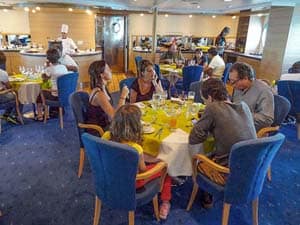 people sitting at a table in a restaurant aboard a ship