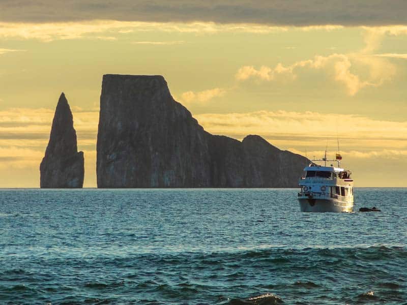 a cruise ship near a huge rock in the ocean