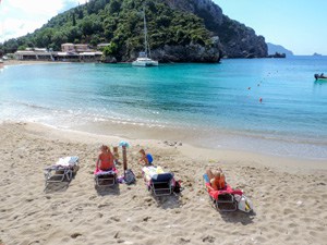 people on a beach by an aquamarine sea