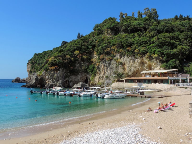 people on a beach near where boats are moored