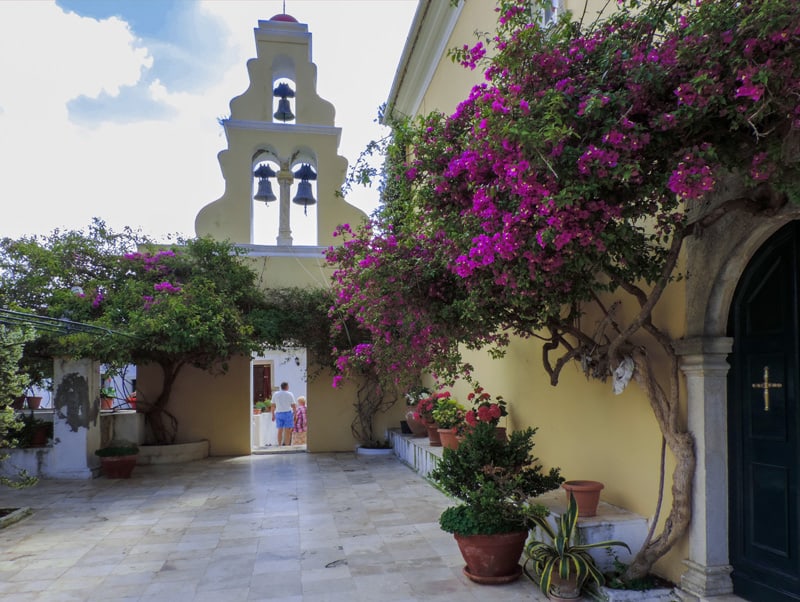 people visiting a monastery with bougainvillea on the walls 