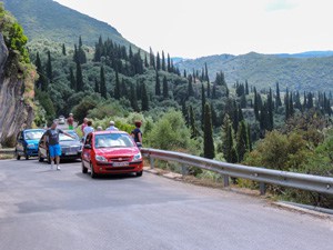 people standing by cars looking at the coastline