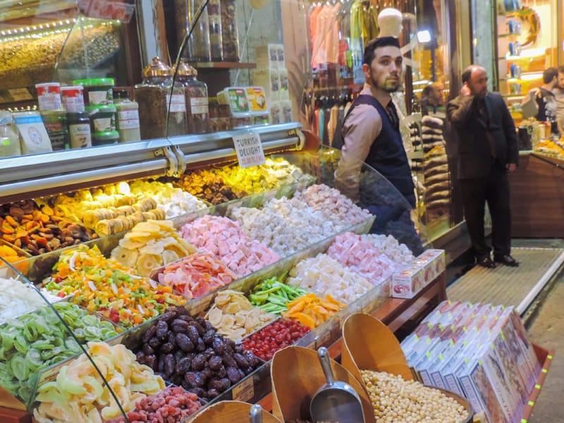 a merchant at a candy display in a bazaar