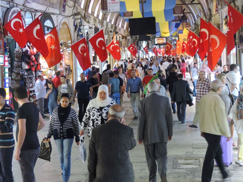 a crowd of people in a bazaar where many red flags hang