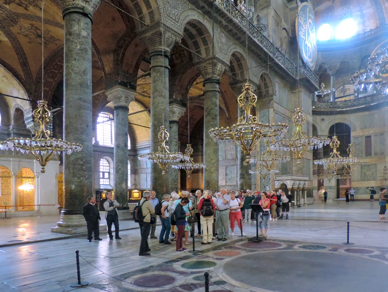 people visiting a mosque looking at large chandeliers, one of the things to do in Istanbul