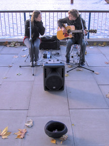 two musicians playing in front of a fence with a hap for tips