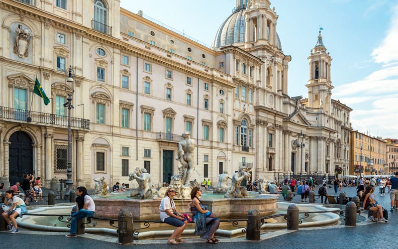people sitting in front of Baroque buildings on the Piazza Navona