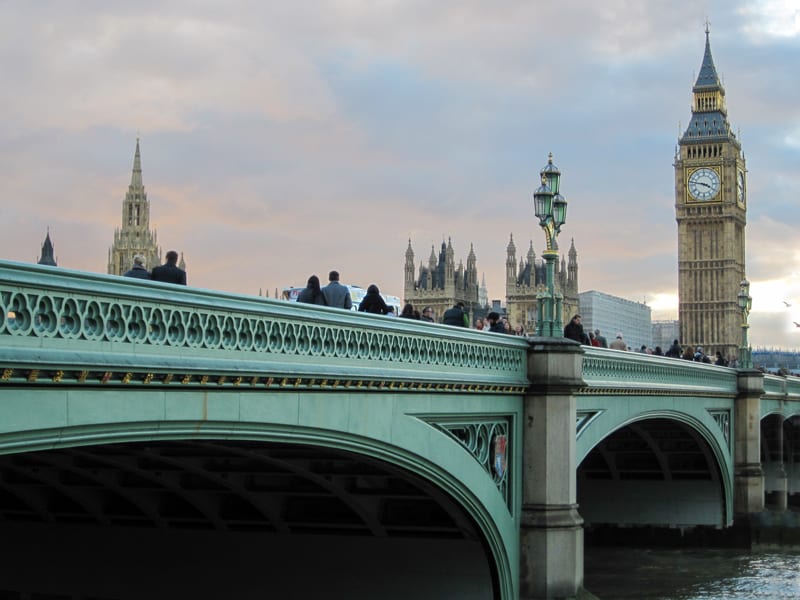 people on a bridge in front of a tall clock tower