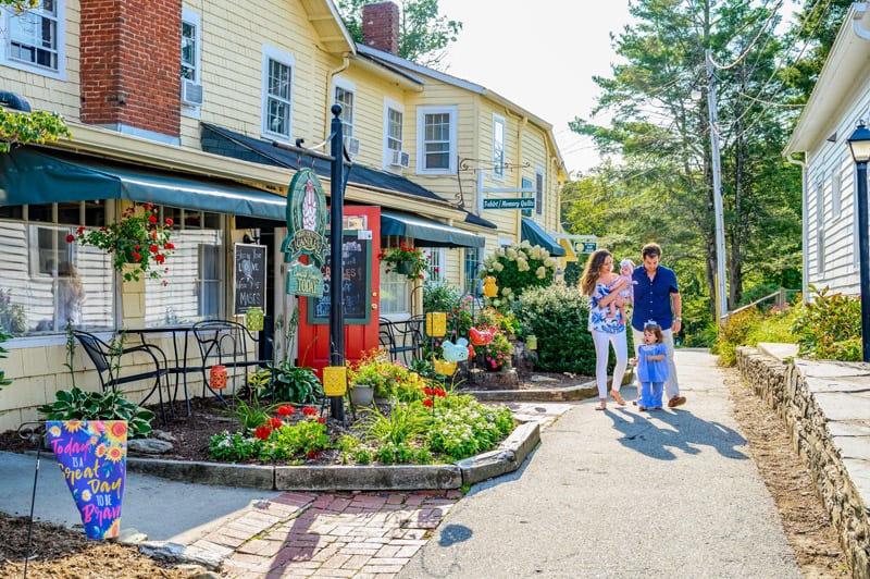 a couple with children walking down a street with cute little stores in the North Carolina High Country