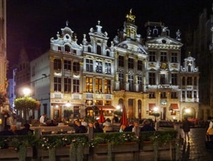 people dining at night by beautiful old floodlit buildings