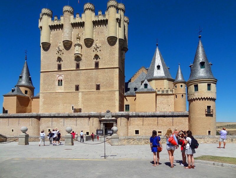 people looking at an ancient castle on a day trip to Segovia from Madrid