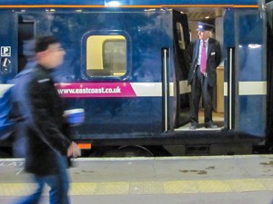 A European train conductor looking out from a train car