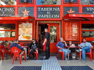 people sitting outside a bar painted a bright red