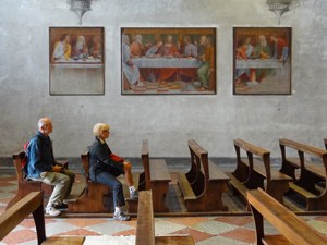 a couple sitting near a fresco of The Last Supper