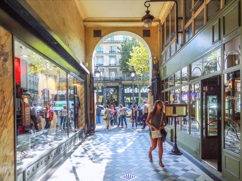 A woman in a passageway walking into a boutique