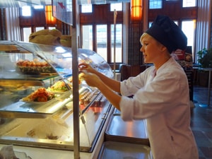 A waitress in a cafe getting dessert for a customer, one of the things to do in Helsinki