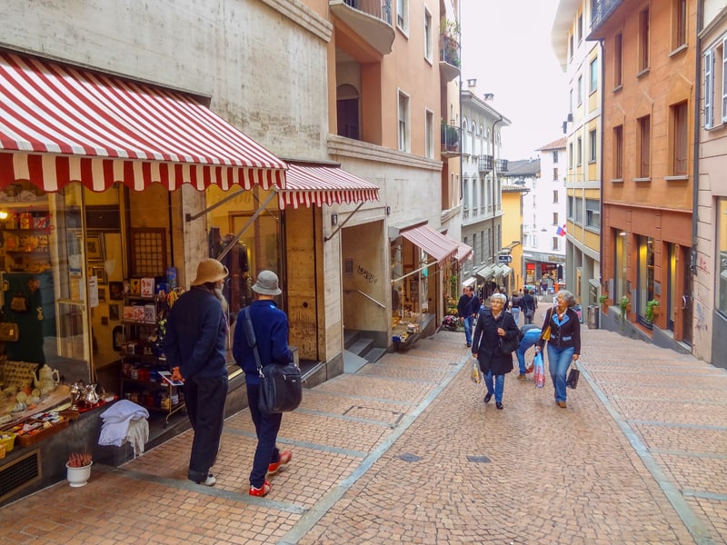 people shopping along a cobblestone street, one of the things to do in Lugano
