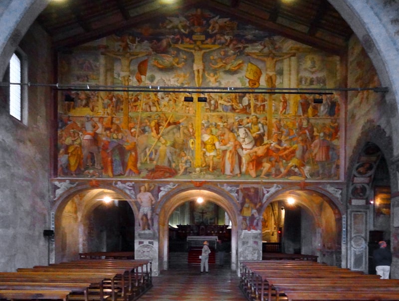 a woman standing beneath a huge fresco in an old church