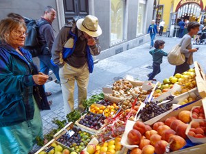 people looking at fruit in a market, one of the things to do in Lugano
