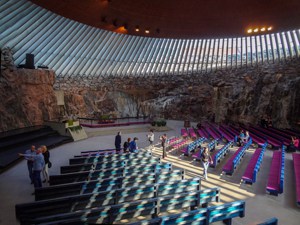 people by colorful pews in a church with stone walls