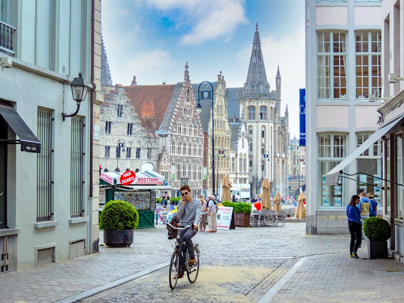 a young man on a bicycle in an old city, one of the things to do in Ghent