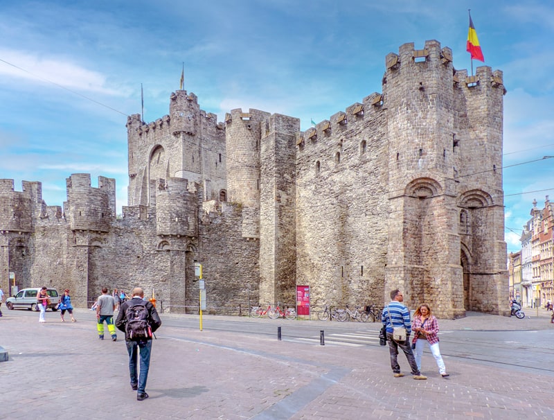 people walking towards a castle in the middle of a city, one of the things to do in Ghent