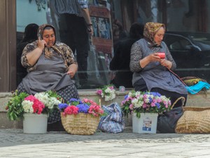 women sitting on a sidewalk selling flowers